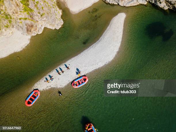 Aerial view of a group of men and women exploring an island in river rafts
