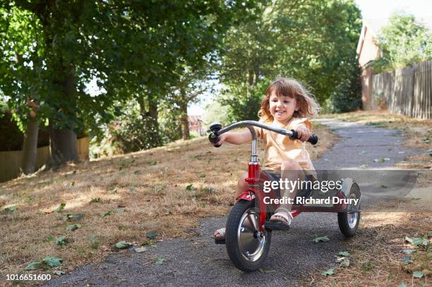 toddler learning to ride her tricycle - dreirad stock-fotos und bilder