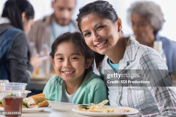 mother and daughter have lunch in soup kitchen - homeless child stock pictures, royalty-free photos & images