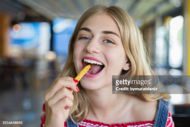 woman eating french fries potato with ketchup - eating chips stock pictures, royalty-free photos & images