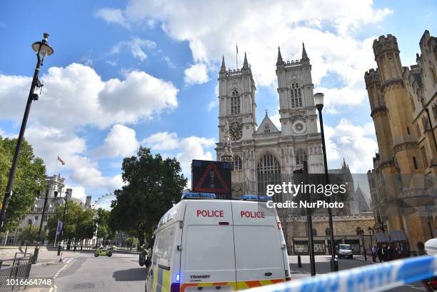 Police officers secure the roads around the Houses of Parliament as forensic teams continue their work around a vehicle after it crashed into...