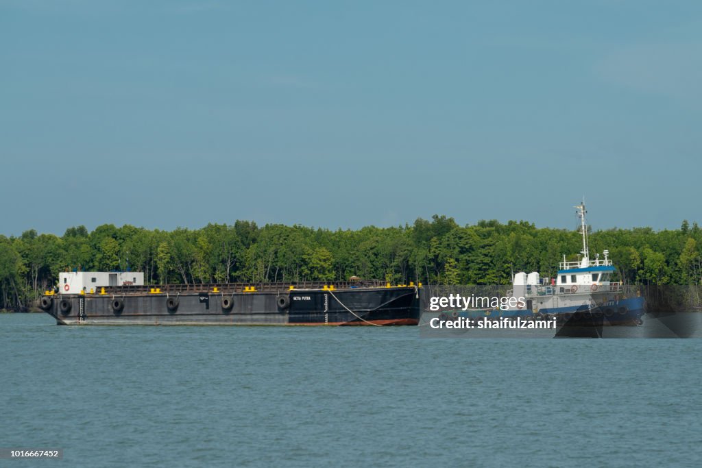 Barge and tug boat cargo ship in Port Klang river.