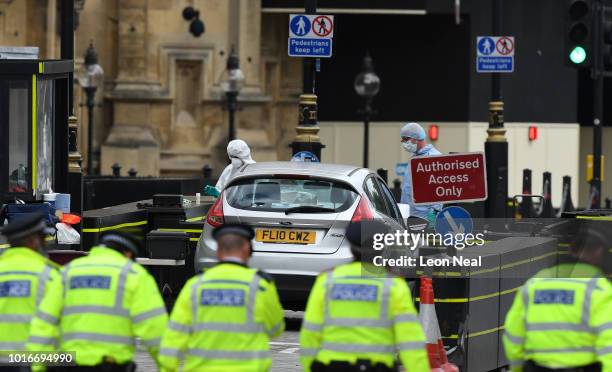 General view of Police officers searching the scene as forensic officers work on the vehicle that crashed into security barriers, injuring a number...