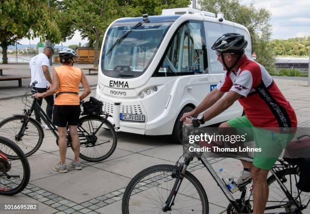 Bicycle riders watch an electric autonomous bus on August 14, 2018 in Mainz, Germany. Called EMMA, the bus is made by Navya and will transport...