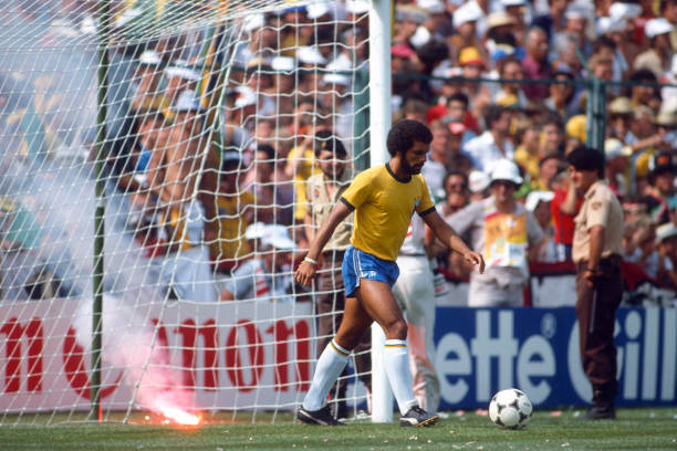 July 1982 - FIFA World Cup - Italy v Brazil - Junior of Brazil retrieves the ball from the net as a flare lands by the goal to celebrate a goal for...