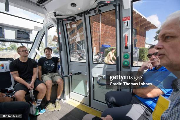 People sit in an electric autonomous bus as it transports passengers on August 14, 2018 in Mainz, Germany. Called EMMA, the bus is made by Navya and...