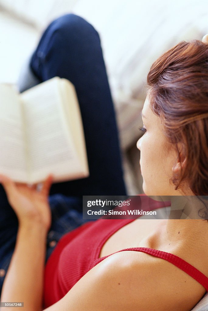 YOUNG WOMAN READING AT HOME