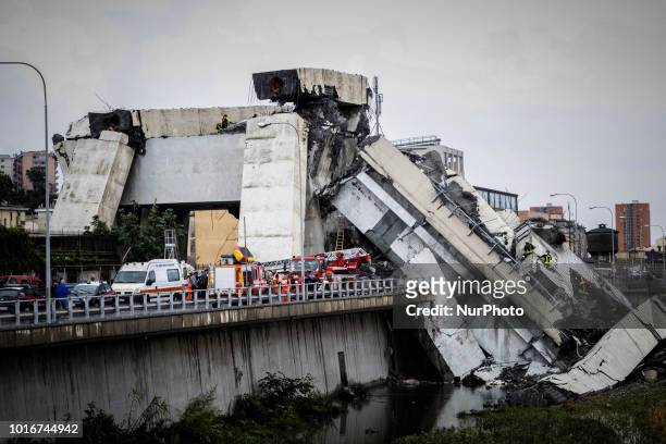 Picture taken on August 14, 2018 shows rescue workers on a part of a Morandi motorway bridge after a section collapsed earlier in Genoa. - At least...