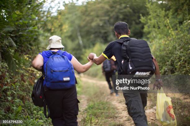 Refugee holds his wife's hand during reaching Croatian border near Velika Kladusa, Bosnia and Herzegovina on August 13, 2018.