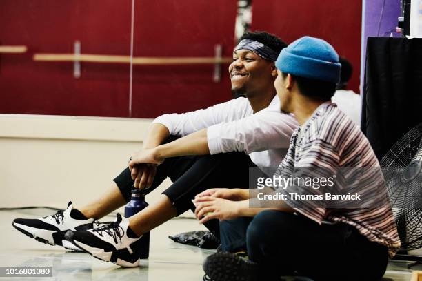 Smiling hip hop dancers relaxing during break in practice in dance studio