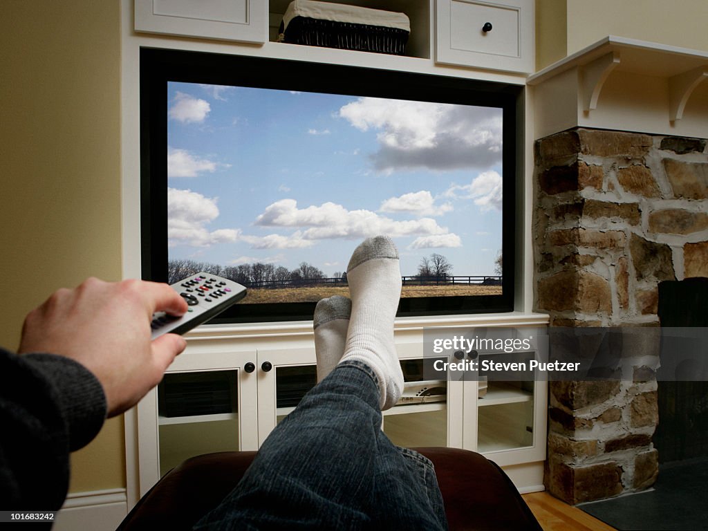 Using remote with feet in front of flat screen