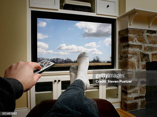 using remote with feet in front of flat screen - man watching tv alone imagens e fotografias de stock