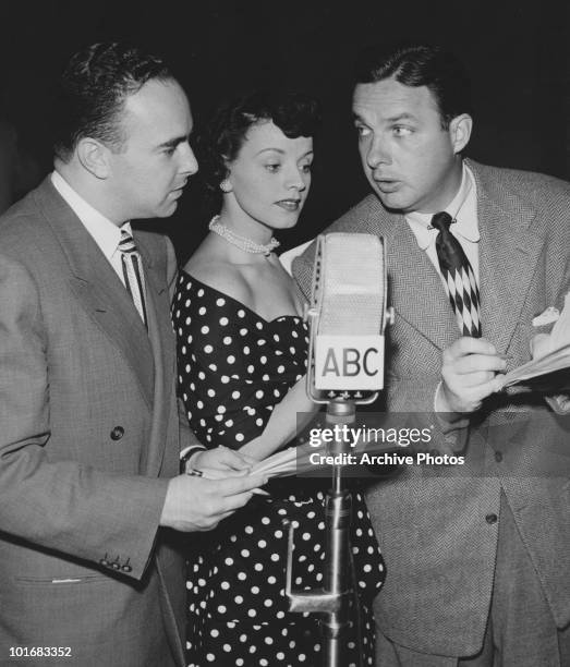 Producer Jack Wormser, singer Kay Starr and bandleader Bob Crosby standing around an ABC microphone discussing a script problem, USA, circa 1950.