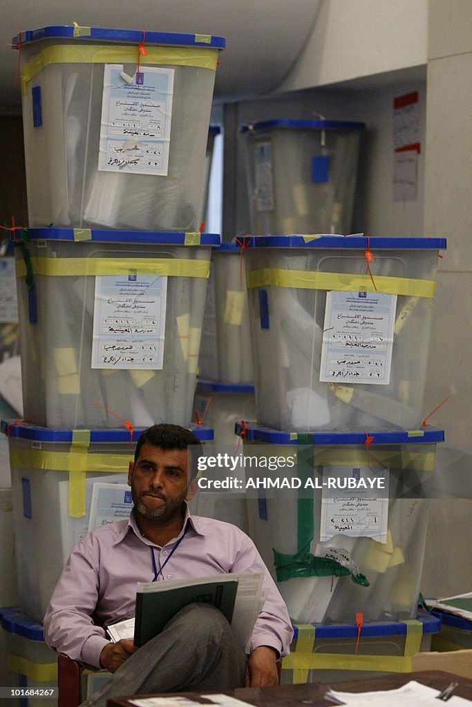 An Iraqi electoral staff sits in front o