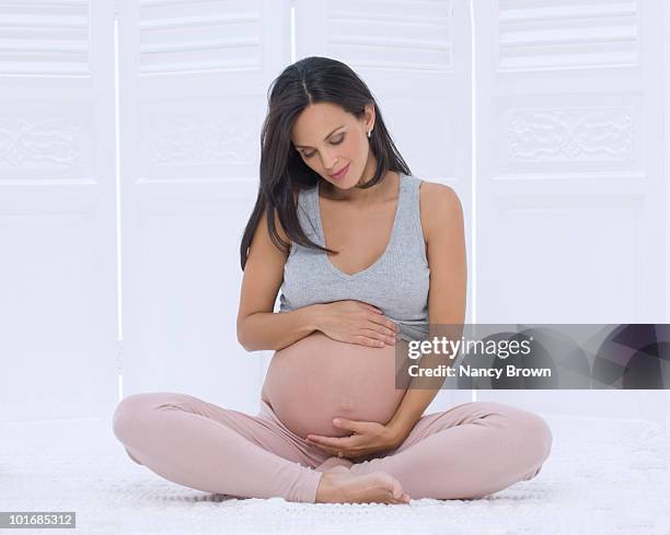pregnant latin woman looking at her stomach. - woman smiling facing down stock pictures, royalty-free photos & images