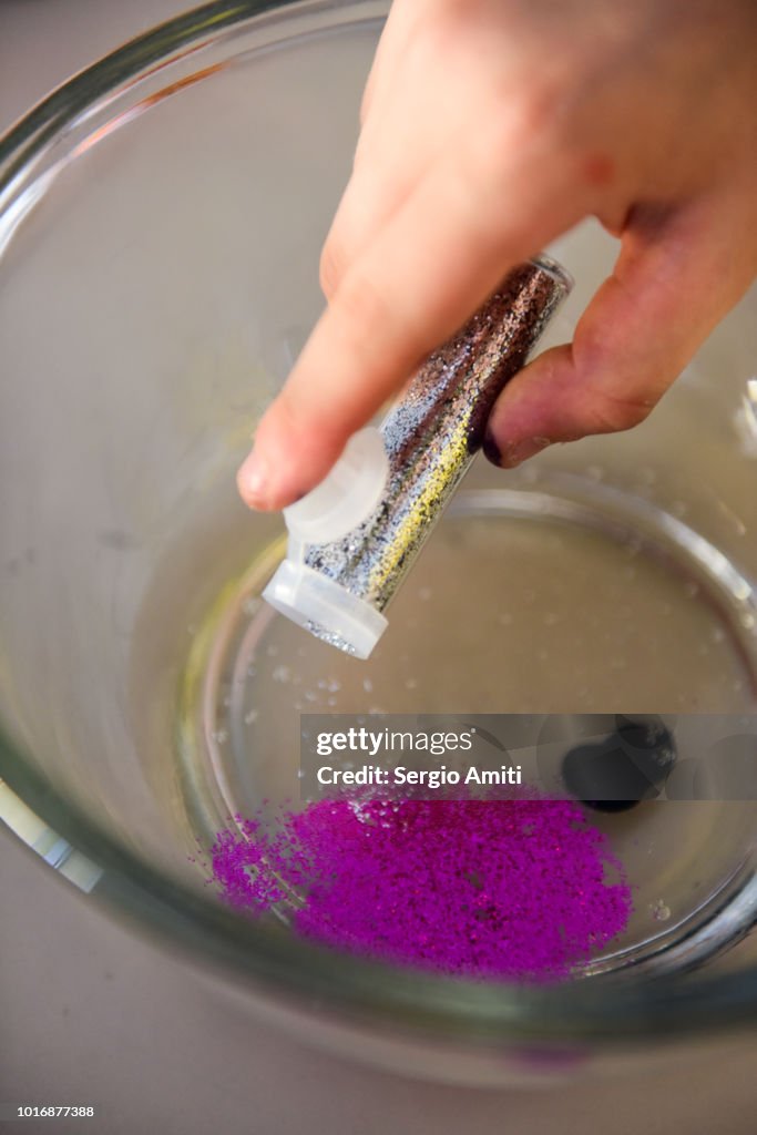 Adding silver glitters into a bowl with water glue and food colouring to make slime