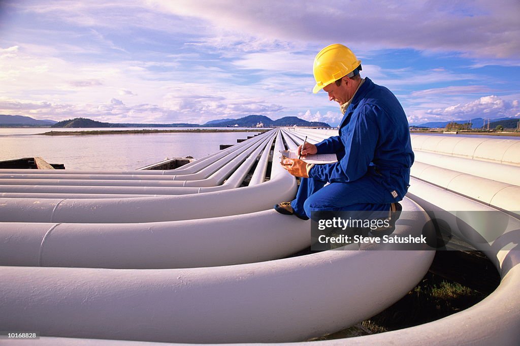 OIL REFINERY WORKER ON PETROLEUM PIPES