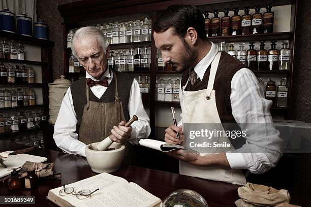 senior pharmacist teaching his apprentice - master of early colour photography stock pictures, royalty-free photos & images