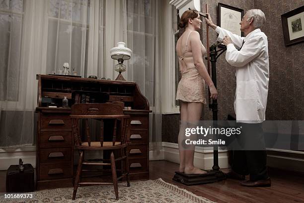 doctor measuring female patient's height - old fashioned doctor stock pictures, royalty-free photos & images
