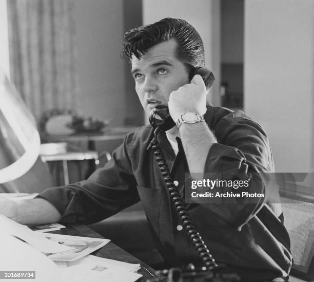 Country music singer and songwriter Conway Twitty talks on the telephone, late 1950s or early 1960s.