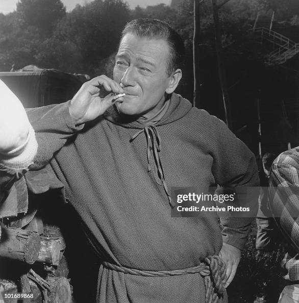 Portrait of American actor John Wayne as he smokes a cigarette on the... News Photo