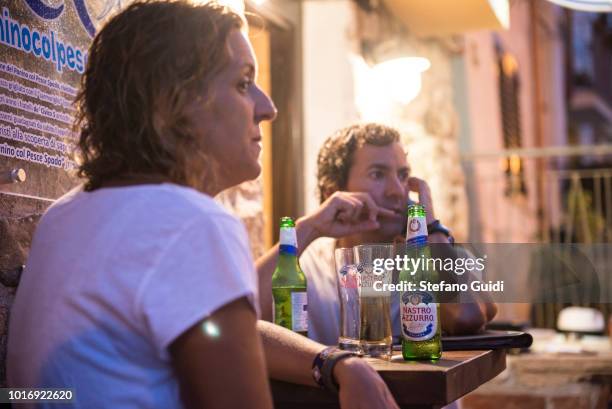 Two guys are waiting for dinner at the table during the nightlife of the Chianalea in Scilla. Chianalea is an ancient district of Scilla, known for...