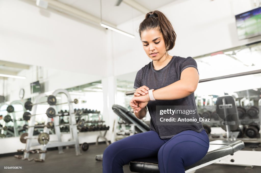 Sporty Female Checking Fitness Activity On Smart Watch In Gym