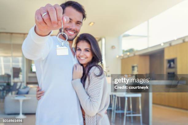 couple tenant une clé de la maison dans leur nouvelle maison. - emprunt immobilier photos et images de collection