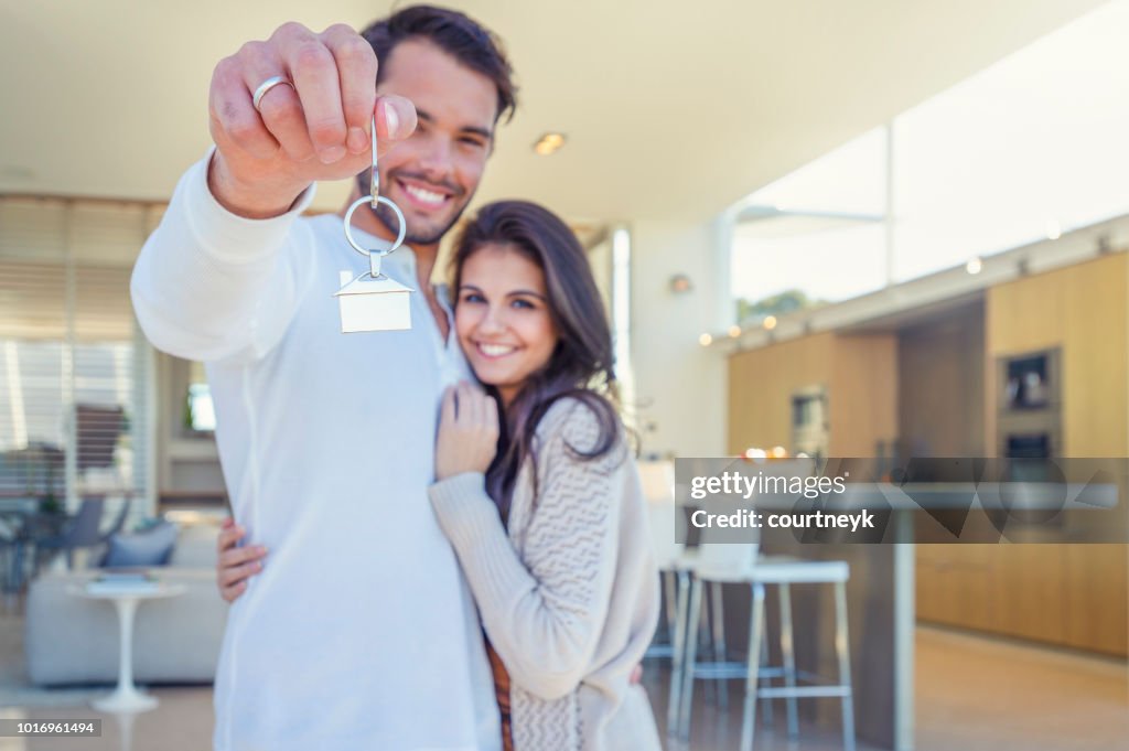 Couple holding a house key in their new home.