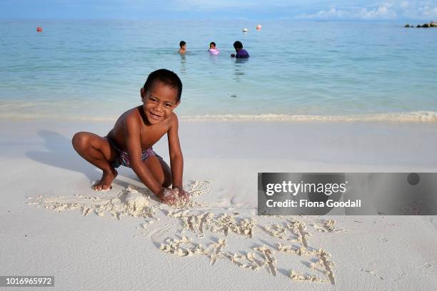 Eloto Terr, 5 writes his name in the sand as his family swim in the lagoon on August 15, 2018 in Funafuti, Tuvalu. The small South Pacific island...