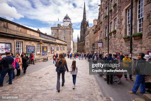 tourists walk along the royal mile near edinburgh castle - castle scotland woman stock pictures, royalty-free photos & images