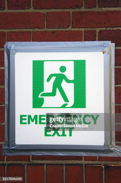 emergency exit sign taped to a the exterior brick wall of a building - 非常口 ストックフォトと画像