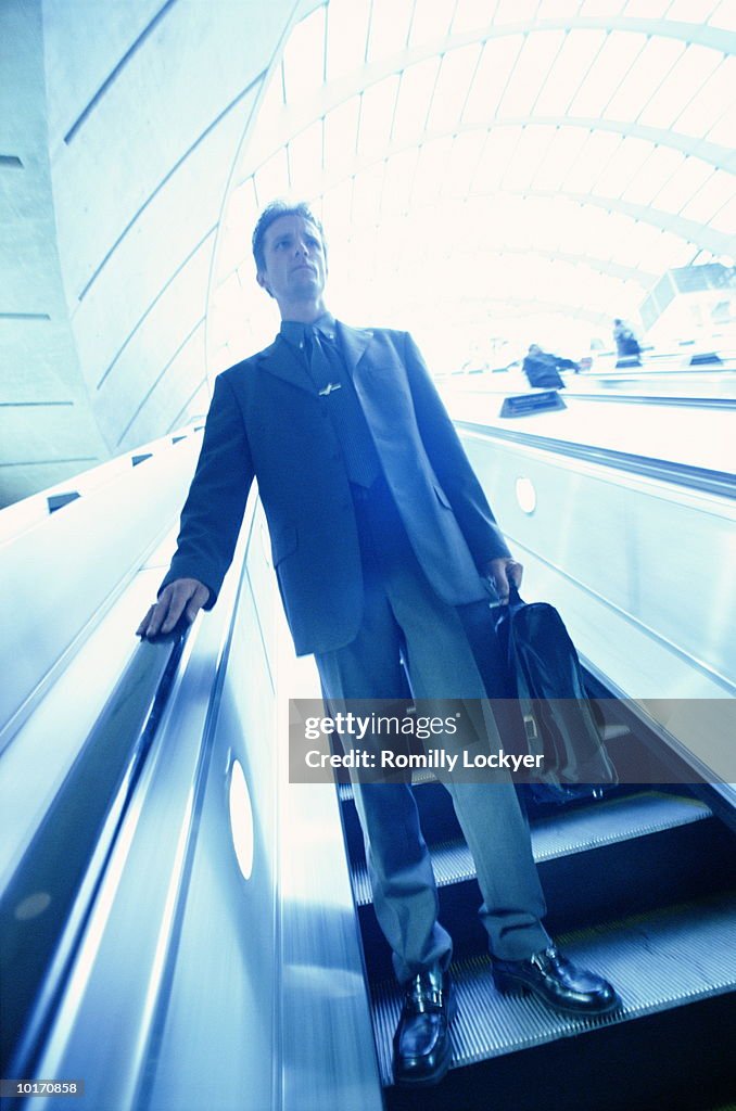 BUSINESSMAN DESCENDING ESCALATOR