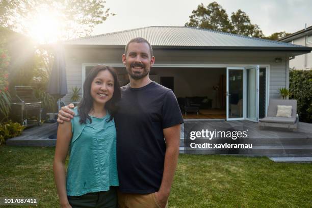 smiling mid adult couple standing against house - australian garden stock pictures, royalty-free photos & images