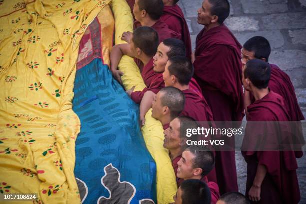 Tibetan Buddhist monks unfold a massive Budda thanka on the first day of the traditional Sho Dun Festival at Drepung Monastery on August 11, 2018 in...