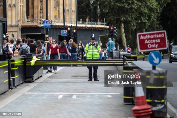 Police officer stands by a security barrier outside the Houses of Parliament, which stopped a speeding vehicle during yesterday morning's incident,...