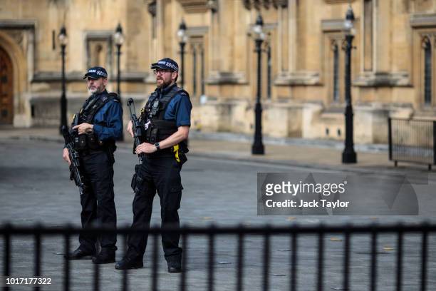 Armed police officers stand behind security barriers outside the Houses of Parliament following yesterday morning's incident, which is being...
