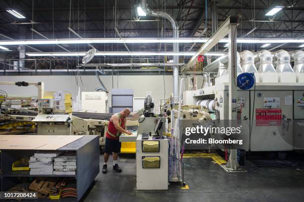 An employee views paperwork in front of a large box assembly machine at the Great Little Box Co. Manufacturing facility in Vancouver, British...