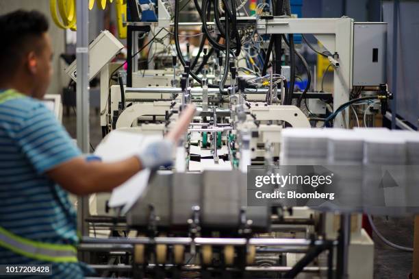 An employee loads printed packing materials into a folding and finishing machine at the Great Little Box Co. Manufacturing facility in Vancouver,...