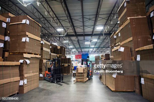 Employees drive forklifts past stacks of raw cardboard at the Great Little Box Co. Manufacturing facility in Vancouver, British Columbia, Canada, on...
