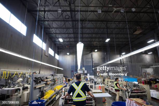 Employees load printed packages into a folding and finishing machine at the Great Little Box Co. Manufacturing facility in Vancouver, British...