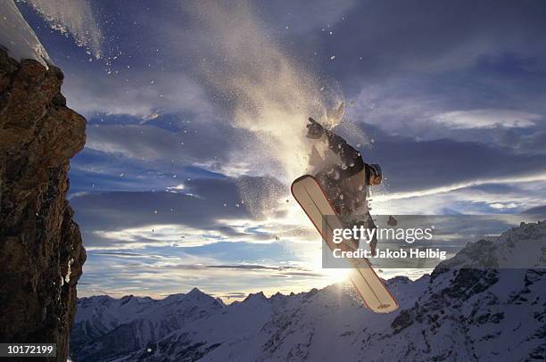 male snowboarder jumping off rock - snowboard jump bildbanksfoton och bilder