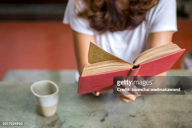 close-up of female hands holding teacup in front of opened book - teenagers reading books stock pictures, royalty-free photos & images