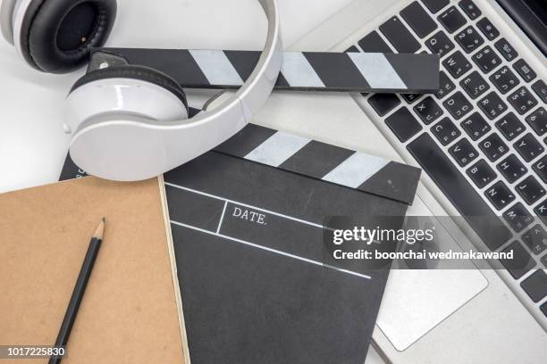 office stuff with movie clapper laptop and coffee cup pen notepad on the wood table top view shot.dark effect - film script stock-fotos und bilder