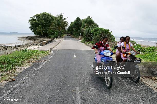 Girls ride home from school across the causeway on August 15, 2018 in Funafuti, Tuvalu. The small South Pacific island nation of Tuvalu is striving...