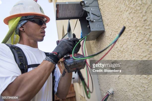 Contractor wires a solar meter box on a new home at the Westline Homes Willowood Cottages community in Sacramento, California, U.S., on Wednesday,...