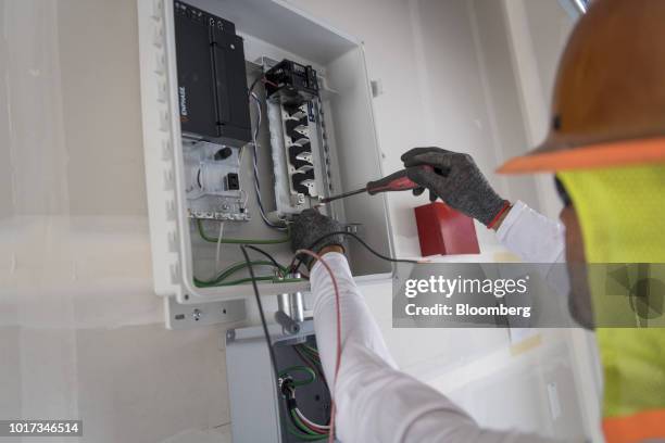 Contractor wires a solar inverter in the garage of a new home at the Westline Homes Willowood Cottages community in Sacramento, California, U.S., on...