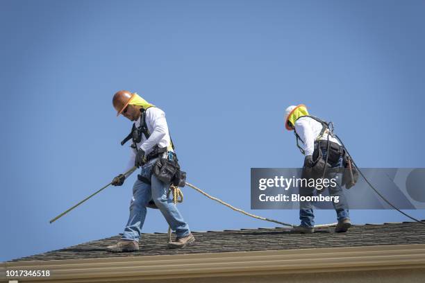 Contractors measure a roof for solar panel installation on a new home at the Westline Homes Willowood Cottages community in Sacramento, California,...