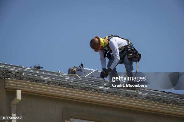 Contractor installs brackets for SunRun Inc. Solar panels on the roof of a new home at the Westline Homes Willowood Cottages community in Sacramento,...