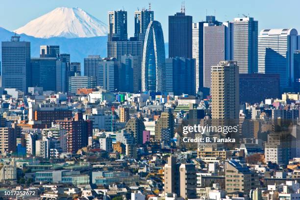 modern shinjuku skyscraper skyline and snowy mt. fuji backdrop in western tokyo, japan - regierungsgebäude der präfektur tokio stock-fotos und bilder